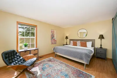 a bedroom with a bed and a chair and a window at Shady Grove with 4 King Beds, Dog Run and Outdoor Fun in Loveland
