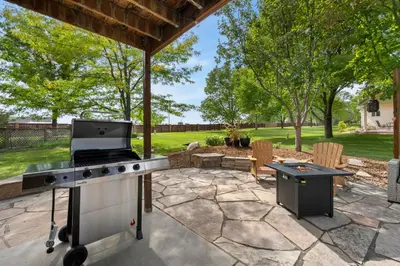 a backyard patio with a grill and a table at Shady Grove with 4 King Beds, Dog Run and Outdoor Fun in Loveland