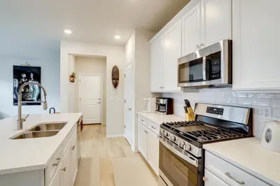 a kitchen with white cabinets and a stove top oven at Less Than 2 Mi to Gaylord Rockies Remote-Work Hub with Gym! in Aurora