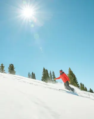 a man riding a snowboard down a snow covered slope at Studio in Lakeside Village, Updated Kitchen & Bath apts in Keystone