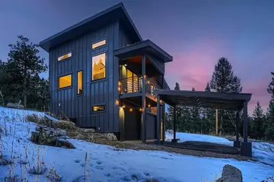 a contemporary house with a black facade in the snow at Pinebox at Evergreen Modern 20Acres -Serene-Creek in Evergreen
