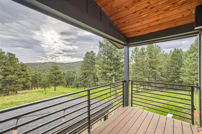 a large deck with a view of the woods at Pinebox at Evergreen Modern 20Acres -Serene-Creek in Evergreen