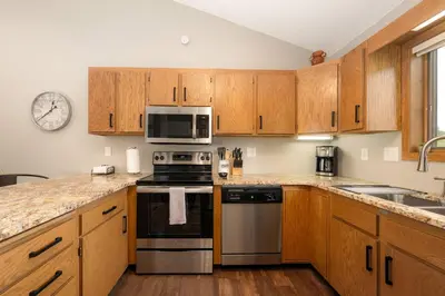 a kitchen with wooden cabinets and a stove and microwave at Bright & Spacious Mtn Retreat in Fraser