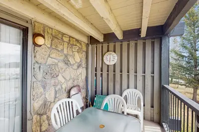 a table and chairs on a porch with a stone wall at Lake Cliffe 209F in Dillon