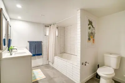 a white bathroom with a shower and a toilet at Game Room and Fire Pit Family-Friendly Loveland Gem in Loveland