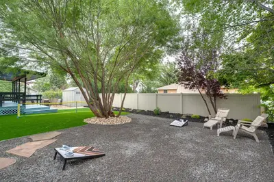 a patio with two chairs and a tree and a playground at Game Room and Fire Pit Family-Friendly Loveland Gem in Loveland