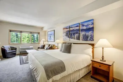 a bedroom with a large white bed and a couch at Gateway Studio - Pool, Hot Tub, Walk to Slopes in Keystone