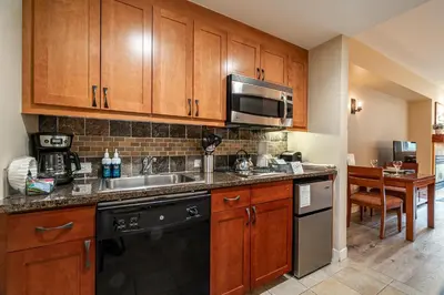 a kitchen with wooden cabinets and a sink and a microwave at Founders Pointe 4569 Ski In Ski Out Winter Park Resort in Winter Park