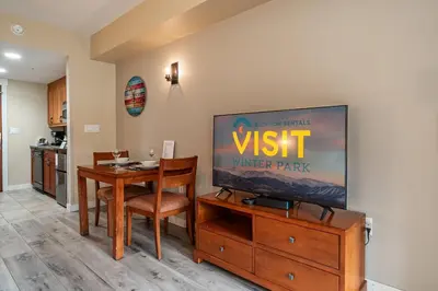 a living room with a tv and a dining table at Founders Pointe 4569 Ski In Ski Out Winter Park Resort in Winter Park
