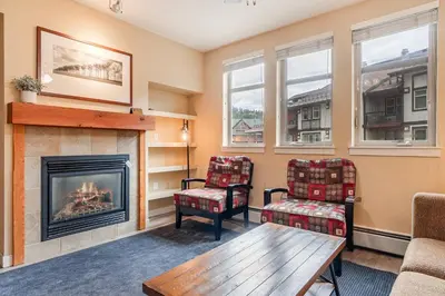 a living room with a fireplace and two chairs at Founders Pointe 4569 Ski In Ski Out Winter Park Resort in Winter Park