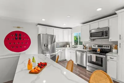 a kitchen with white cabinets and a table with fruit on it at 5BD Japanese-Themed w/ Hot Tub, Movie Room & Games in Arvada
