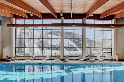 a large swimming pool with chairs and a large window at 1-Bedroom plus Loft at The Pines with Forest Views, No Cleaning Fees, Kids Ski Free condo in Keystone