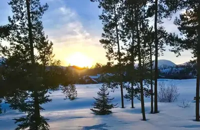 a snowy field with trees and the sunset in the background at 1-Bedroom plus Loft at The Pines with Forest Views, No Cleaning Fees, Kids Ski Free condo in Keystone