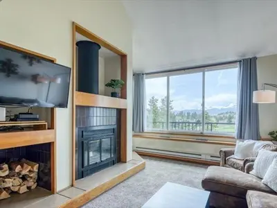 a living room with a fireplace and a large window at 1-Bedroom plus Loft at The Pines with Forest Views, No Cleaning Fees, Kids Ski Free condo in Keystone