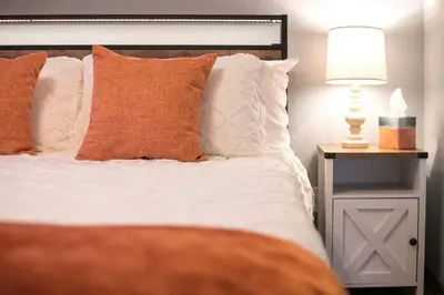 a bed with orange and white pillows and a lamp at Luxury Spacious House Great for a Family Retreat in Loveland