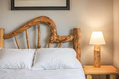 a bed with a wooden headboard and a table with a lamp at 3BR Paws & Relax by Sweetheart Stays in Loveland