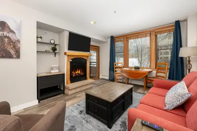 a living room with a red couch and a fireplace at Ski-In Ski-Out Zephyr 1 Bedroom Condo 2204 in Winter Park