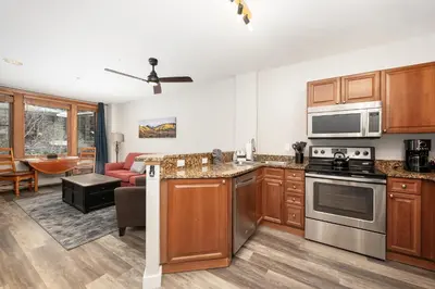 a kitchen with stainless steel appliances and a living room at Ski-In Ski-Out Zephyr 1 Bedroom Condo 2204 in Winter Park