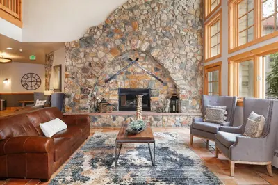 a living room with a stone fireplace and leather furniture at Expedition Station 8574 in Keystone