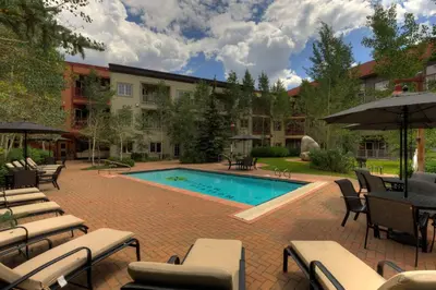 a pool with chairs and umbrellas next to a building at Expedition Station 8553 in Keystone