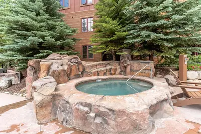 a large stone pool with a spa in a yard at Springs 8887 in Keystone