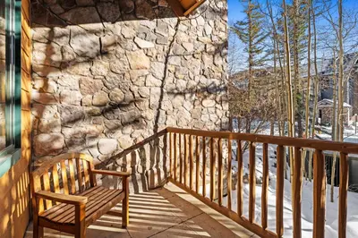 a wooden bench sitting on a porch with a stone wall at Arap Ldg 8101 in Keystone