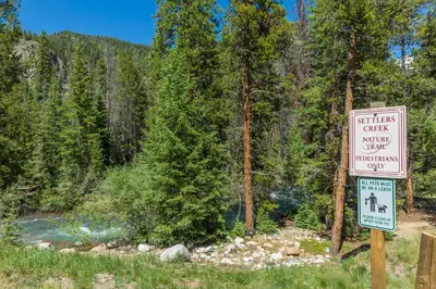 a sign in front of a river with trees at Red Hawk Lodge 2271 : 300 in Keystone