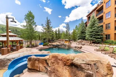 a swimming pool in a resort with a large rock at Springs 8845 in Keystone
