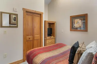 a bedroom with a bed and a wooden cabinet at Red Hawk Lodge 2312 in Keystone
