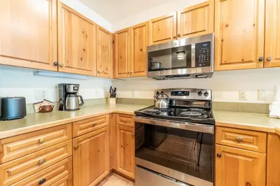 a kitchen with wooden cabinets and a stove and microwave at Expedition Station 8581 in Keystone