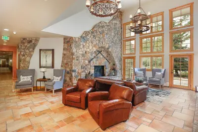a living room with a stone fireplace and leather chairs at Expedition Station 8576 in Keystone