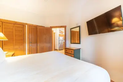 a bedroom with a white bed and a flat screen tv at Expedition Station 8569 in Keystone