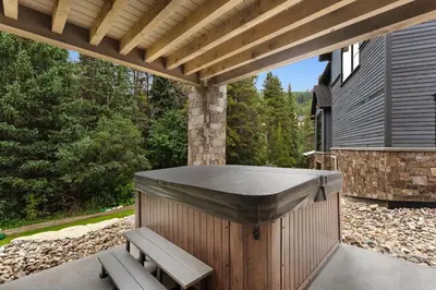 a wooden pergola with a bench on a patio at Alcove 77 in Keystone