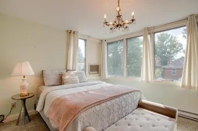 a bedroom with a bed and a chandelier and windows at Victorian-Style Cheesman Park Apt - 2 Mi to Dtwn in Denver