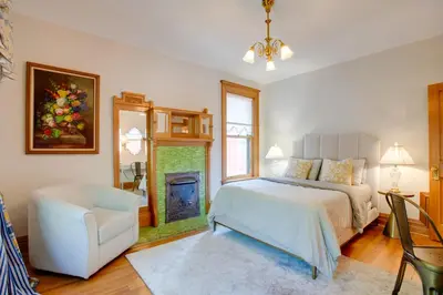 a bedroom with a bed and a chair and a fireplace at Victorian-Style Cheesman Park Apt - 2 Mi to Dtwn in Denver