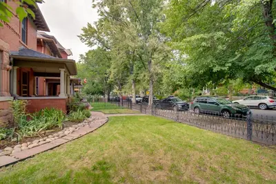 a fence in front of a house with parked cars at Victorian-Style Cheesman Park Apt - 2 Mi to Dtwn in Denver