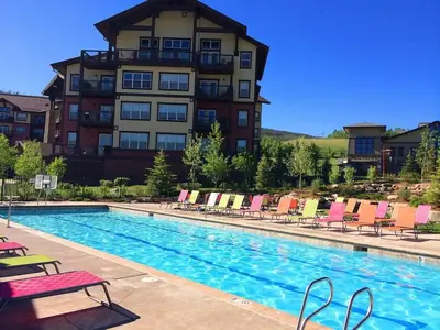 a hotel with a swimming pool with chairs and a building at 2 BR Basecamp Bliss at Kicking Horse Near Ski Hill in Granby