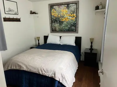 a bedroom with a bed and a painting on the wall at Railway Cabin at Base Camp in Dumont