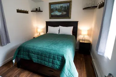 a bedroom with a bed with a green comforter and two lamps at Miners Cabin at Base Camp Lodging Company in Dumont