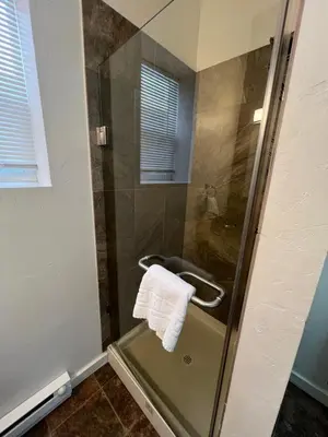 a bathroom with a shower with a towel on a glass door at Miners Cabin at Base Camp Lodging Company in Dumont