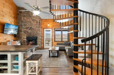 a spiral staircase in a living room with a stone wall at Rocky Mountain Retreat in Granby