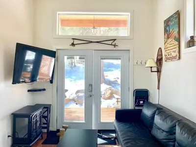 a living room with a couch and a sliding glass door at Spring Gulch Cabin at Base Camp in Dumont