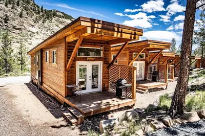 a tiny house in the woods with a porch at Spring Gulch Cabin at Base Camp in Dumont