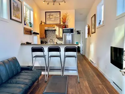 a living room with a couch and a bar with stools at Spring Gulch Cabin at Base Camp in Dumont