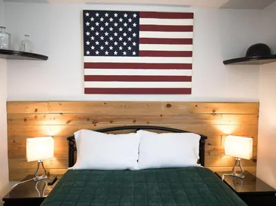 an american flag hanging above a bed with two lamps at Iron Horse Cabin at Base Camp Lodging Company in Dumont