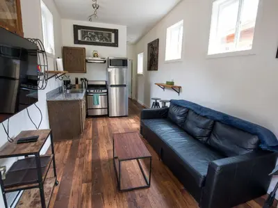 a living room with a black leather couch and a kitchen at Iron Horse Cabin at Base Camp Lodging Company in Dumont