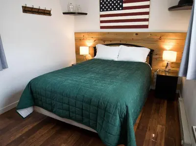 a bed in a room with an american flag on the wall at Iron Horse Cabin at Base Camp Lodging Company in Dumont