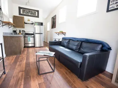 a black leather couch in a living room with a kitchen at Iron Horse Cabin at Base Camp Lodging Company in Dumont