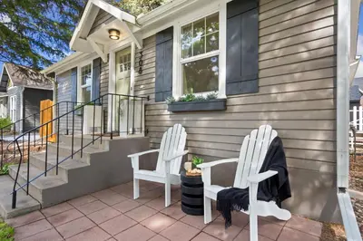 two white chairs sitting on the front porch of a house at Shade Tree Bungalow in Old Town, Yard & Garage in Fort Collins