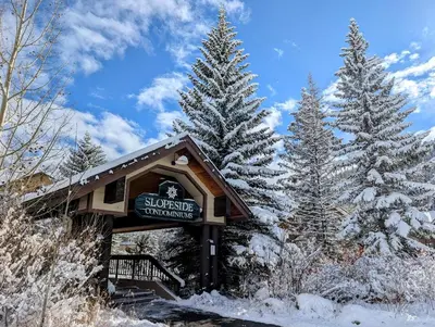 a sign for a ski lodge with snow covered trees at Slopeside 2768A by SummitCove Lodging in Keystone